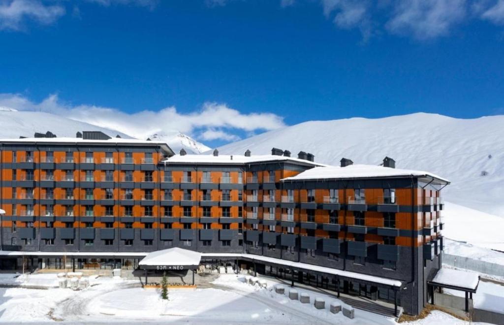 a hotel in the snow in front of a mountain at New Gudauri Two Bedroom Apartment Neo Building in Gudauri