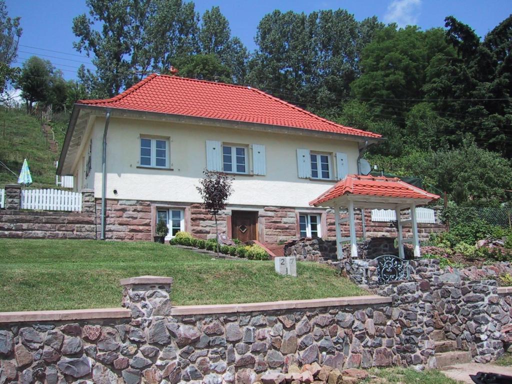 une maison avec un toit rouge et un mur en pierre dans l'établissement Villa Roma, à Losheim