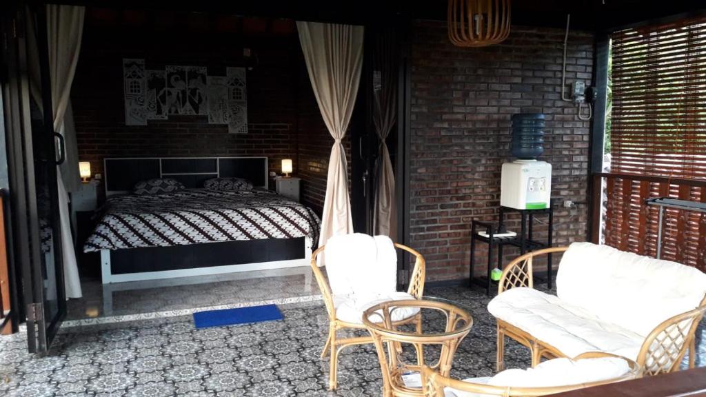 a bedroom with a bed and chairs on a patio at omah linares in Celep