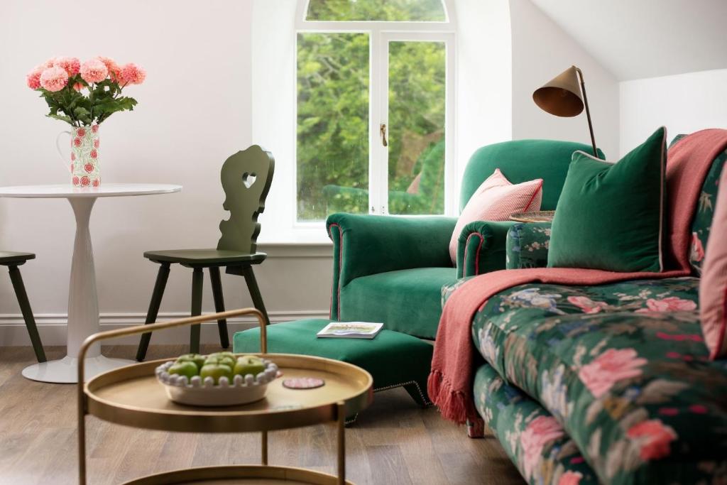 a living room with a green couch and a table at The Hayloft, Kailzie in Peebles