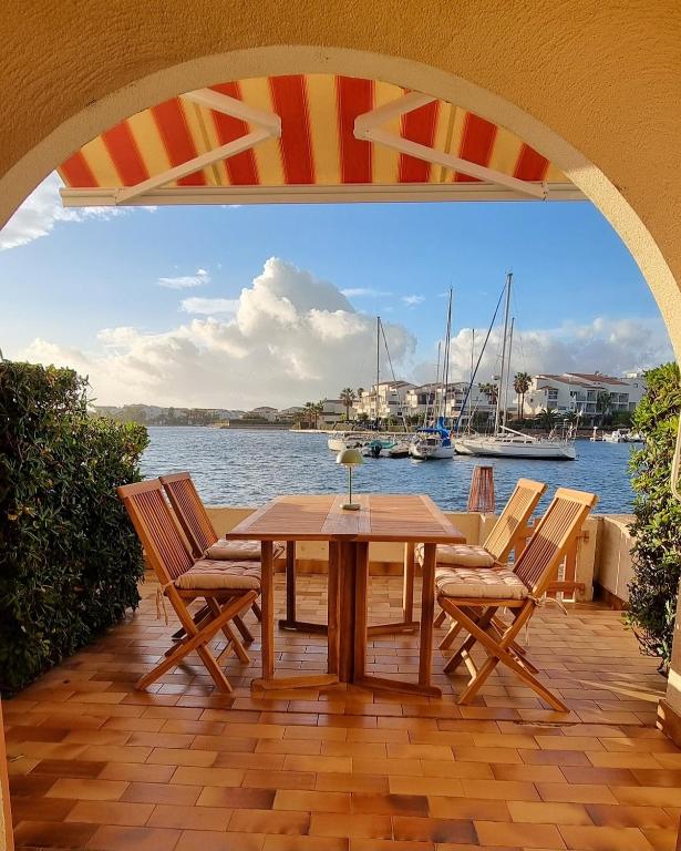 - une table et des chaises sur une terrasse avec vue sur l'eau dans l'établissement Maison de vacances unique, au bord de la mer, proche plages, à Saint Cyprien Plage