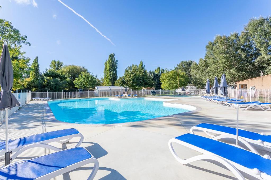 une piscine avec des chaises bleues et des parasols dans l'établissement Camping Bel Air Village Les Prés du Verdon, à Quinson