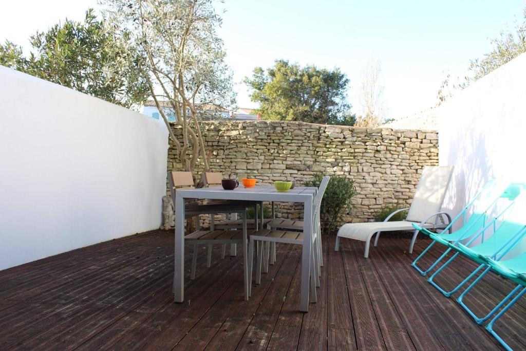 une table et des chaises sur une terrasse avec un mur en briques dans l'établissement Appt 3 pièces ILE DE RE - IDR400-010, à Saint-Martin-de-Ré