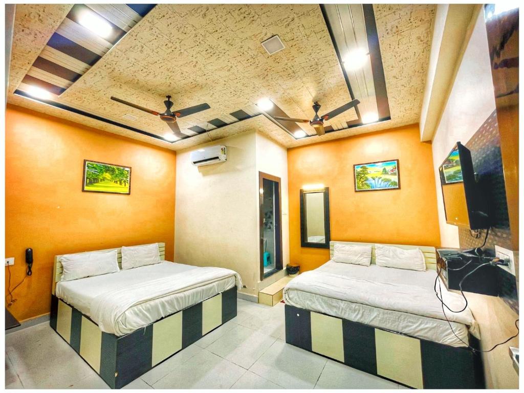 two beds in a room with orange walls at Hotel Pragati Heights in Mathura