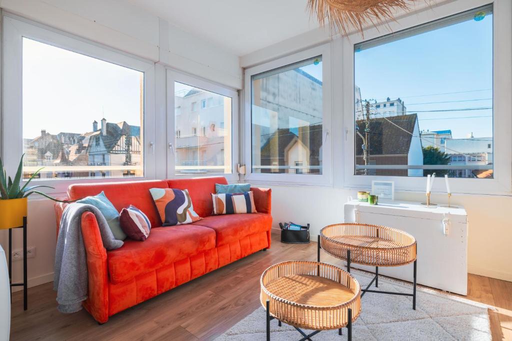 a living room with a red couch and some windows at Les Oiseaux-2 chambres idéalement placé proche plage et centre in Le Touquet-Paris-Plage