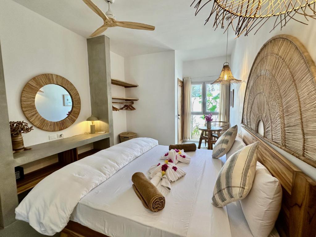 Un dormitorio con una gran cama blanca y un espejo. en Beachfront Apartments with Private Pool, en Kiwengwa