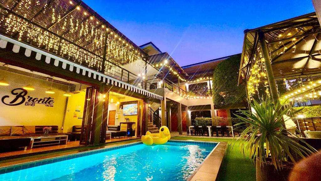 a house with a swimming pool in front of it at Bronte BnB in Cha Am