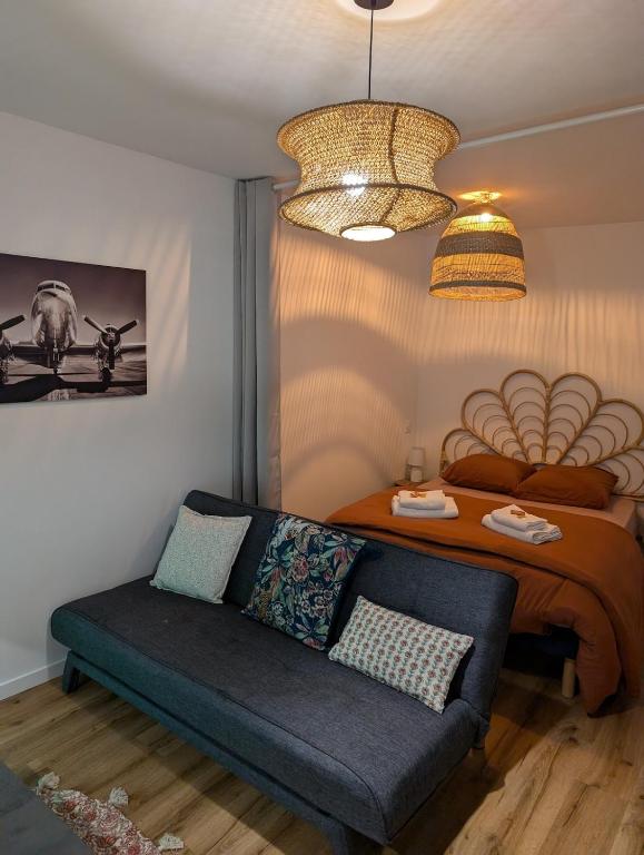 a living room with a couch and a bed at Charmant studio au coeur de la ville in Guer