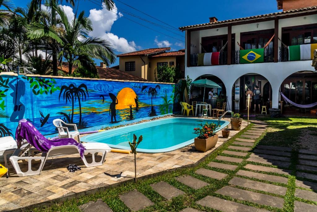 a swimming pool in front of a house with a mural at Geckos Hostel in Florianópolis