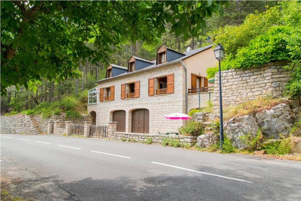 une maison avec un parasol sur le côté d'une route dans l'établissement Location a chanteperdrix 2 personnes, à Sainte-Énimie