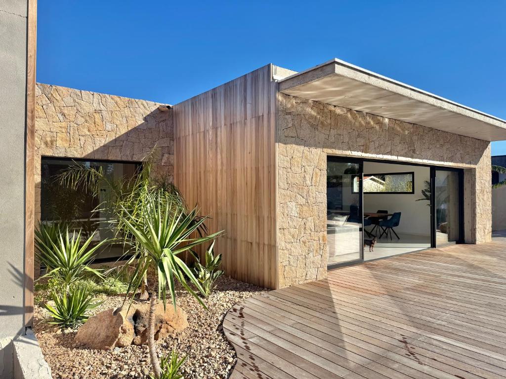 une maison en pierre avec une terrasse en bois devant elle dans l'établissement Villa Porto-Vecchio avec piscine, à Lecci