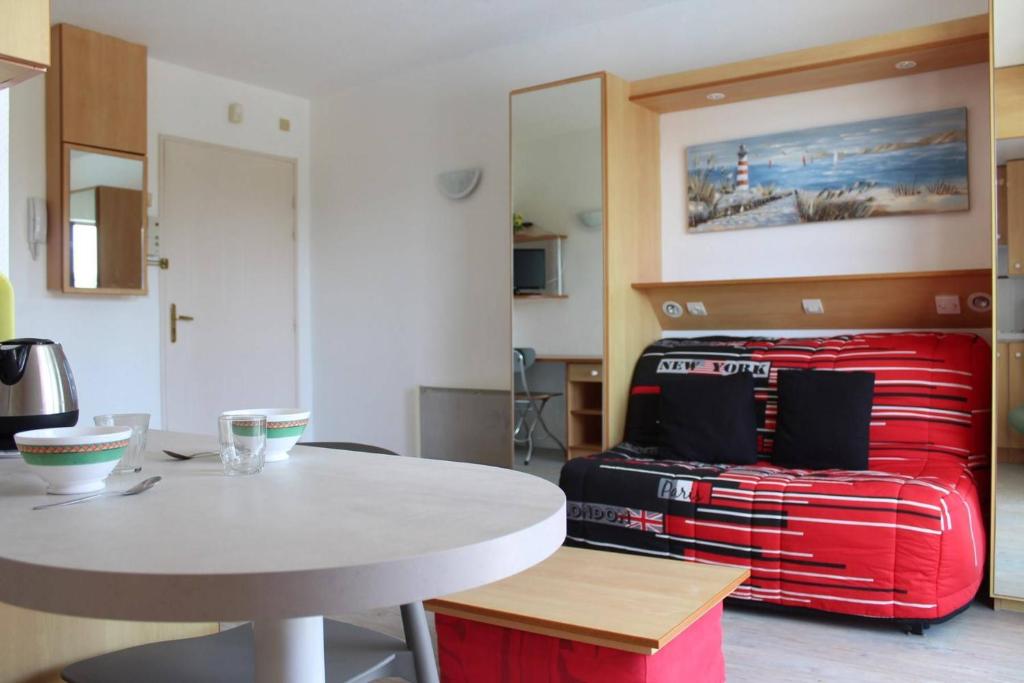 une chambre avec une table et un lit avec une valise rouge dans l'établissement Studio LA ROCHELLE - LR010-205, à La Rochelle