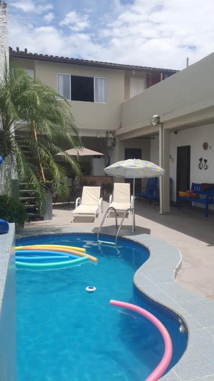 una piscina con sombrilla, 2 sillas, mesa y sombrilla en Pousada chc, en Praia Grande