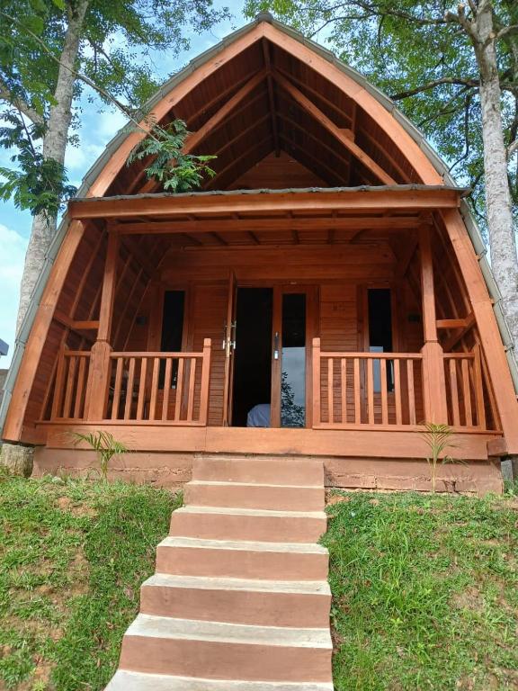 a log home with a staircase leading to a porch at Naraya Nusantara Resort & Kafe in Sepaku