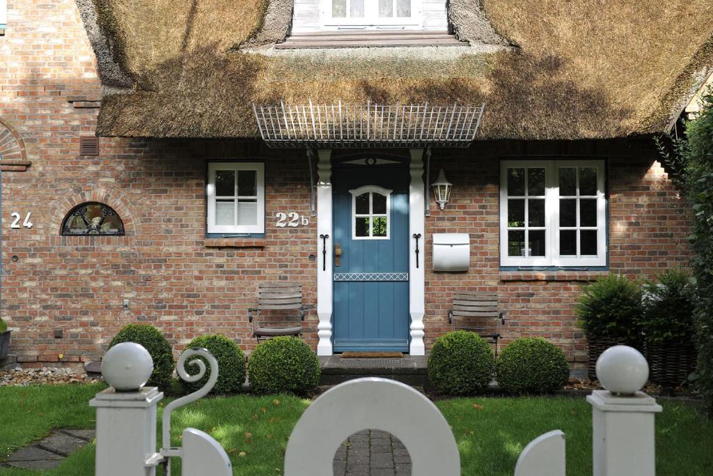 a house with a blue door and a thatch roof at Bahnhofstraße 22B in Keitum