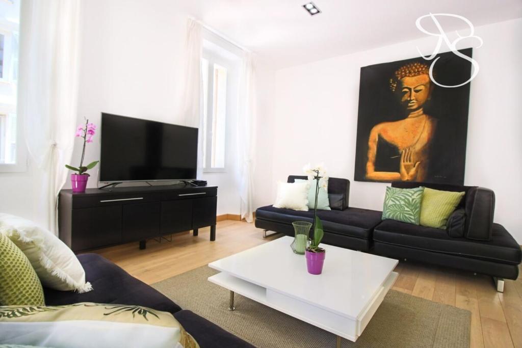 un salon avec un canapé noir et une télévision dans l'établissement Renovated 3 bedrooms with patio - heart of Cannes, à Cannes