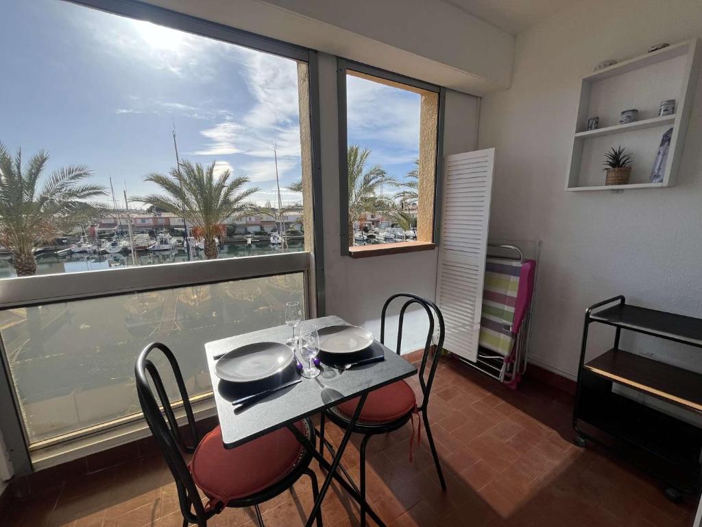 une table et des chaises dans une pièce avec une fenêtre dans l'établissement Appartement Studio- Vue Port - Cap d'Agde CT040-020, au Cap d'Agde