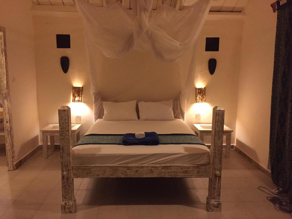 a bedroom with a bed with two lights on it at Black Marlin - Kadidiri in Batudaka