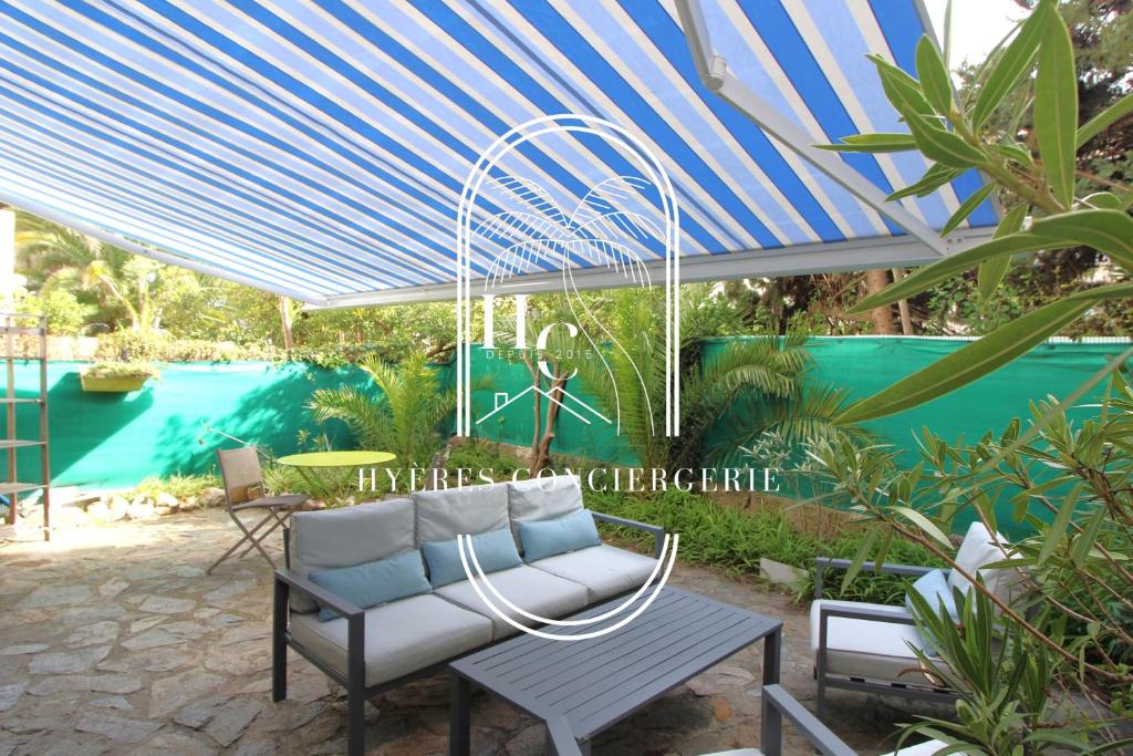 une terrasse avec un parasol bleu et blanc et une chaise dans l'établissement Duplex au coeur du Port d'Hyères- Plages Parking BY HC, à Hyères