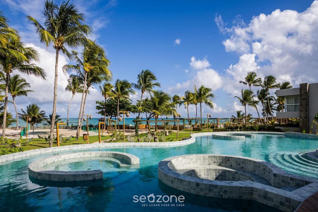 une piscine dans un complexe hôtelier avec des palmiers dans l'établissement NLU - Condomínio completo na Praia do Marceneiro, à Barra do Camaragibe