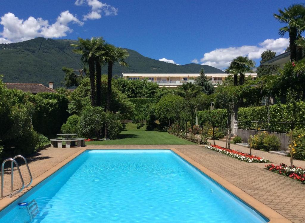 a swimming pool in a yard with a building in the background at Lido Golf by Fewotessin in Ascona