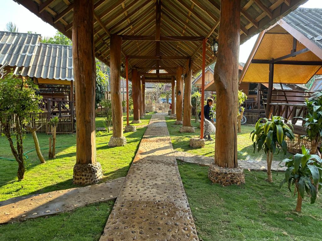 une personne marchant sous un pavillon en bois dans un parc dans l'établissement Nearthepark Resort at Pai, à Pai