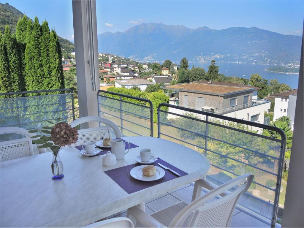 a white table and chairs on a balcony with a view at Residenza al Castagno Duplex by Fewotessin in Piazzogna