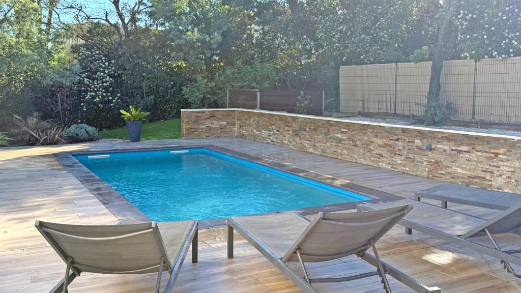 a swimming pool in a yard with two chairs and a table at Villa Pré d'Icard in Plan-de-la-Tour