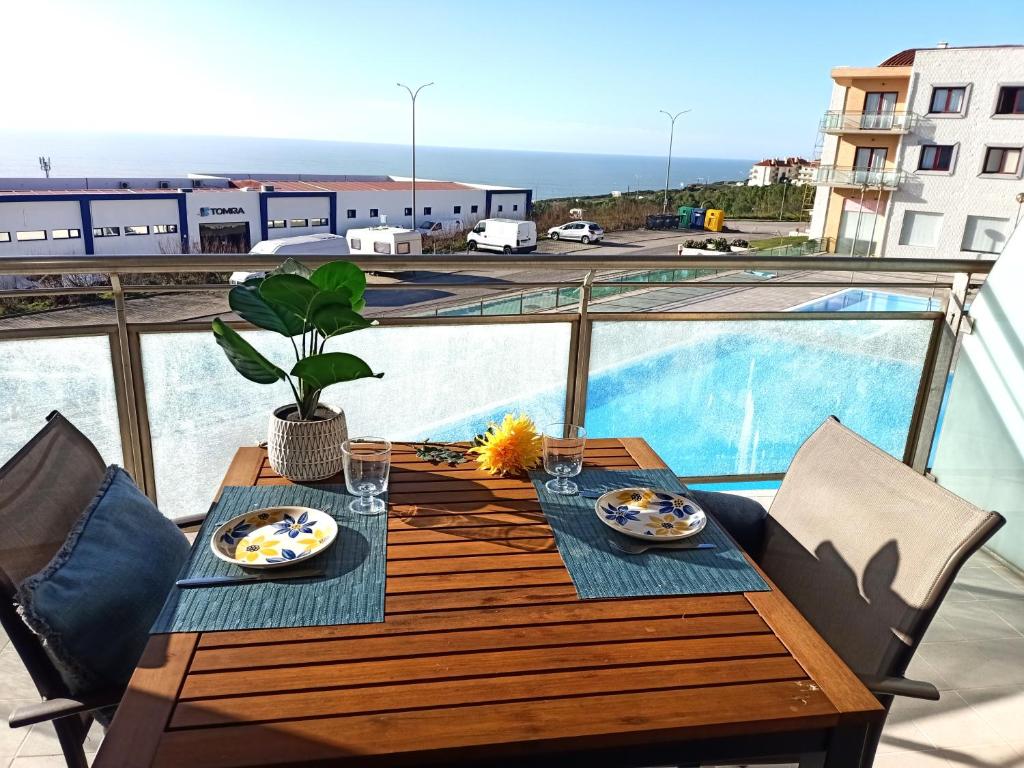 a wooden table with plates of food on a balcony at Like-Home-T1-Sun & Beach-Pools, AC in Ericeira
