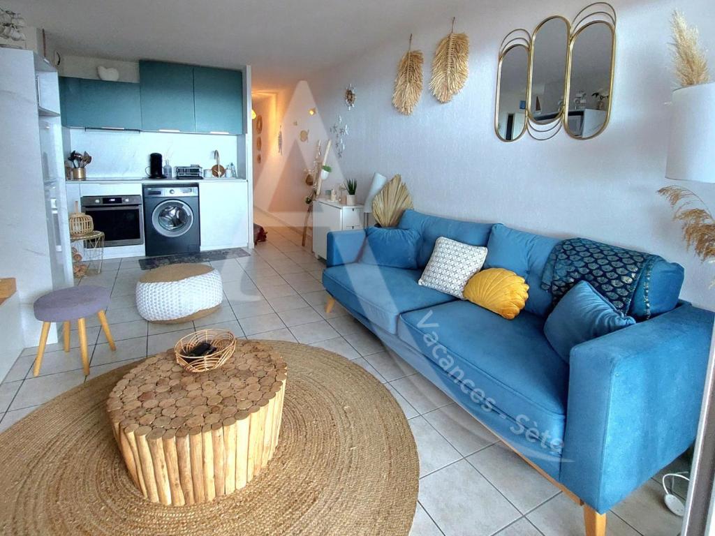 un salon avec un canapé bleu et une cuisine dans l'établissement T3 avec grande terrasse et vue panoramique sur la mer, à Sète