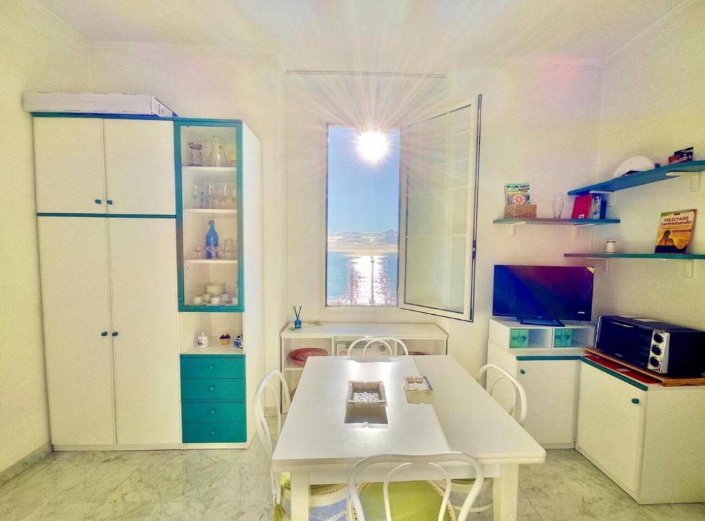 une cuisine avec une table blanche et une fenêtre dans l'établissement Bilocale Fronte Mare, à Menton
