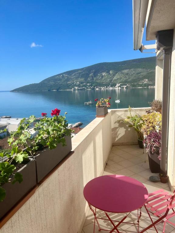 a balcony with a table and chairs and a view of the water at Panoramic Bliss in Herceg Novi in Herceg-Novi