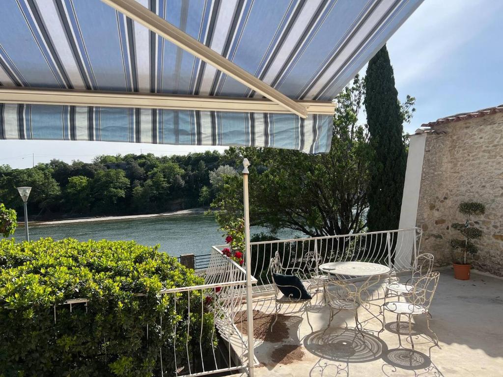 a patio with a table and chairs and a view of a river at La Batisse de Reve in Saint-Martin-dʼArdèche