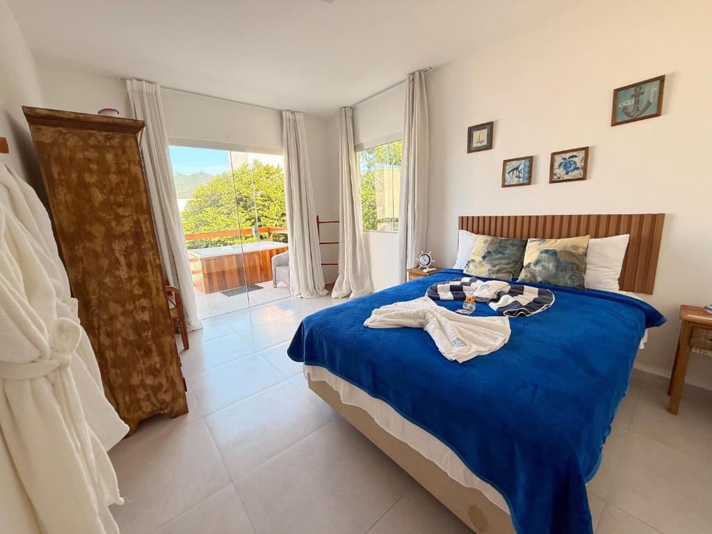 een slaapkamer met een bed met blauwe lakens en een raam bij Suíte Atenas com hidro aquecida - Arraial do Cabo in Arraial do Cabo