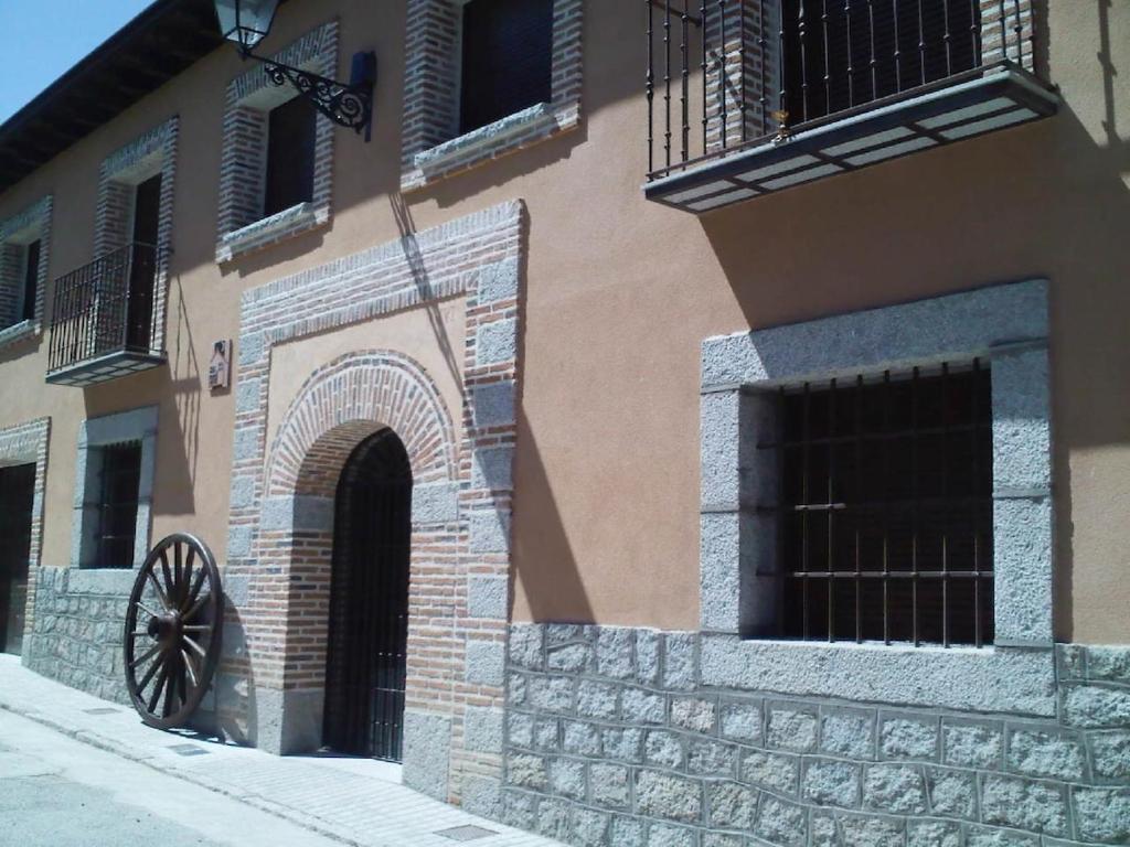 a building with an arch and a wheel on the side at La Casa Madrona-Completa in Villacastín