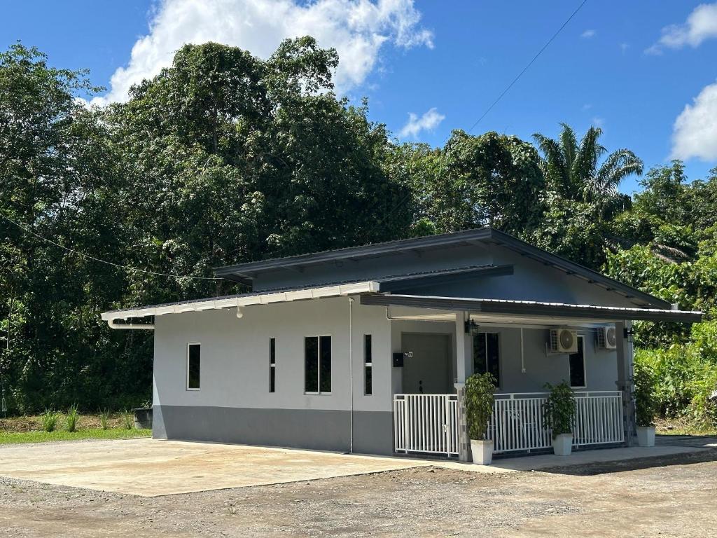 a small white house with trees in the background at Rumah Singgah Beaufort Homestay in Beaufort