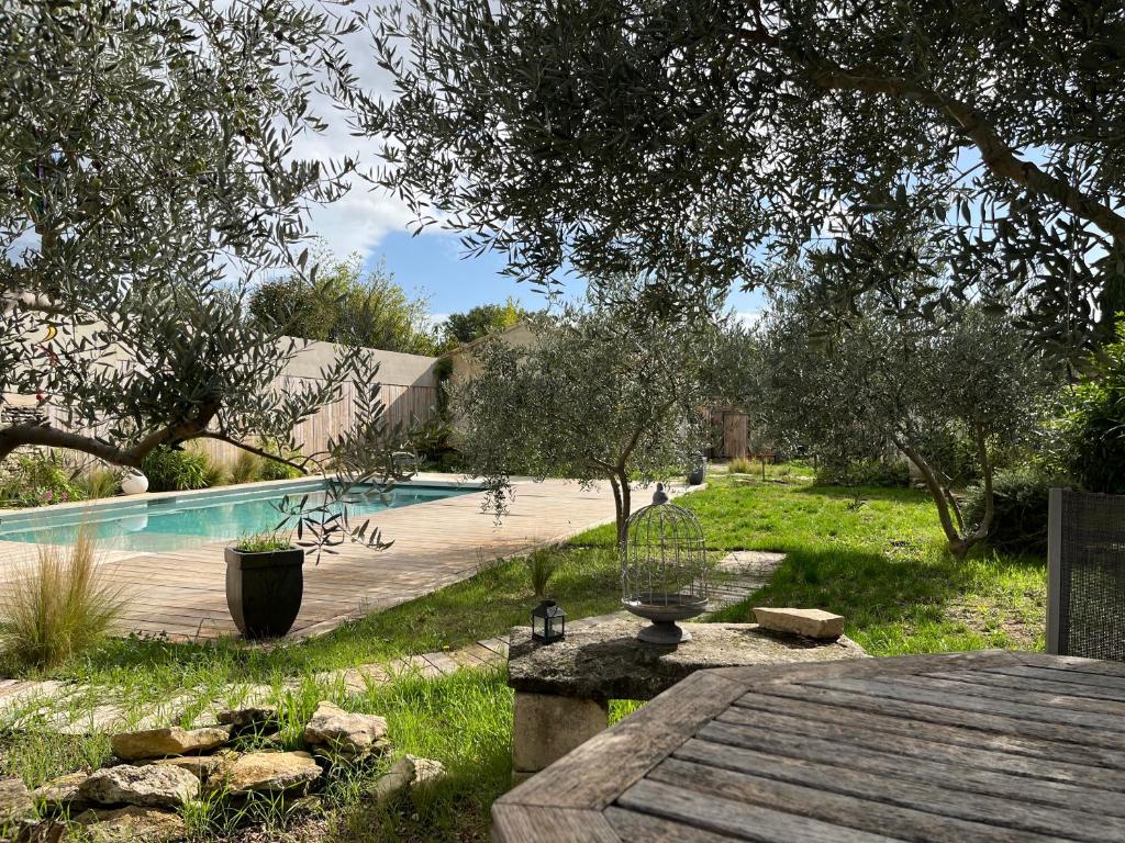 une arrière-cour avec une piscine et une table en bois dans l'établissement Le jardin secret, à Gordes