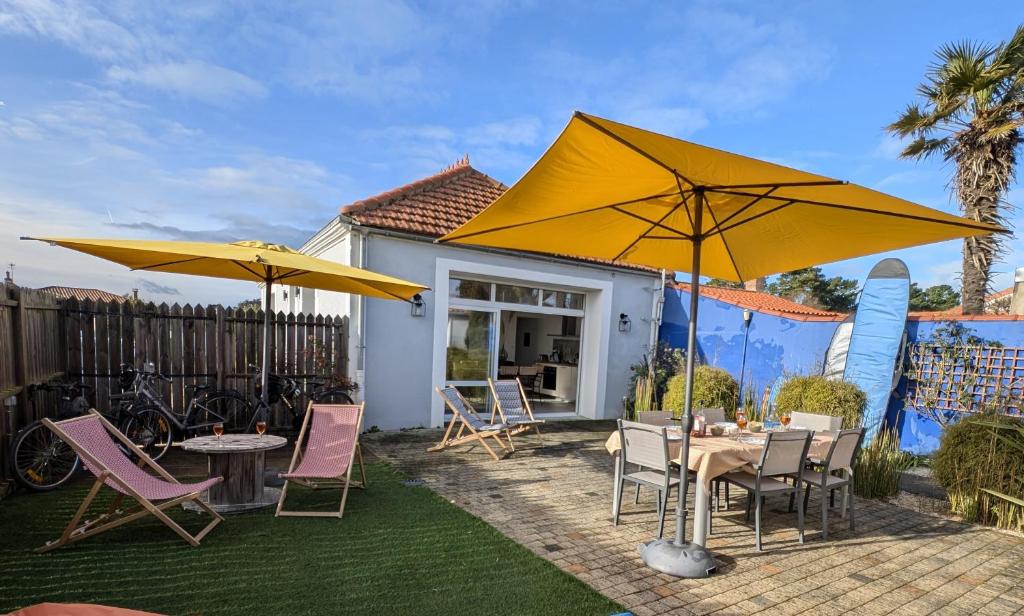 un patio avec des tables, des chaises et des parasols dans l'établissement La Fleur de Sel, à Les Sables-dʼOlonne