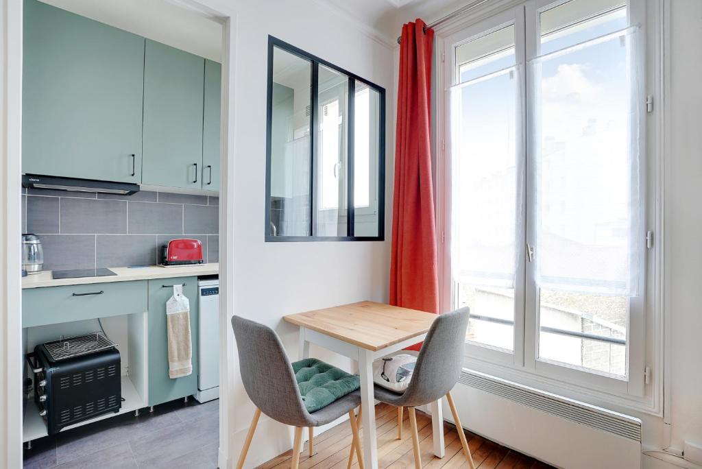 une cuisine avec une table et deux chaises ainsi qu'une fenêtre dans l'établissement Studio Lumineux au pied du RER A - Avec ascenseur, à Vincennes
