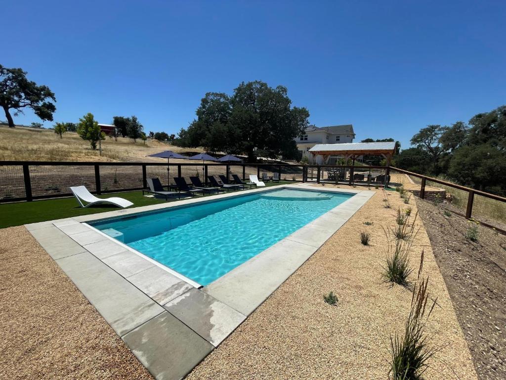 a swimming pool with chairs and a fence at Graceful Oaks in Paso Robles