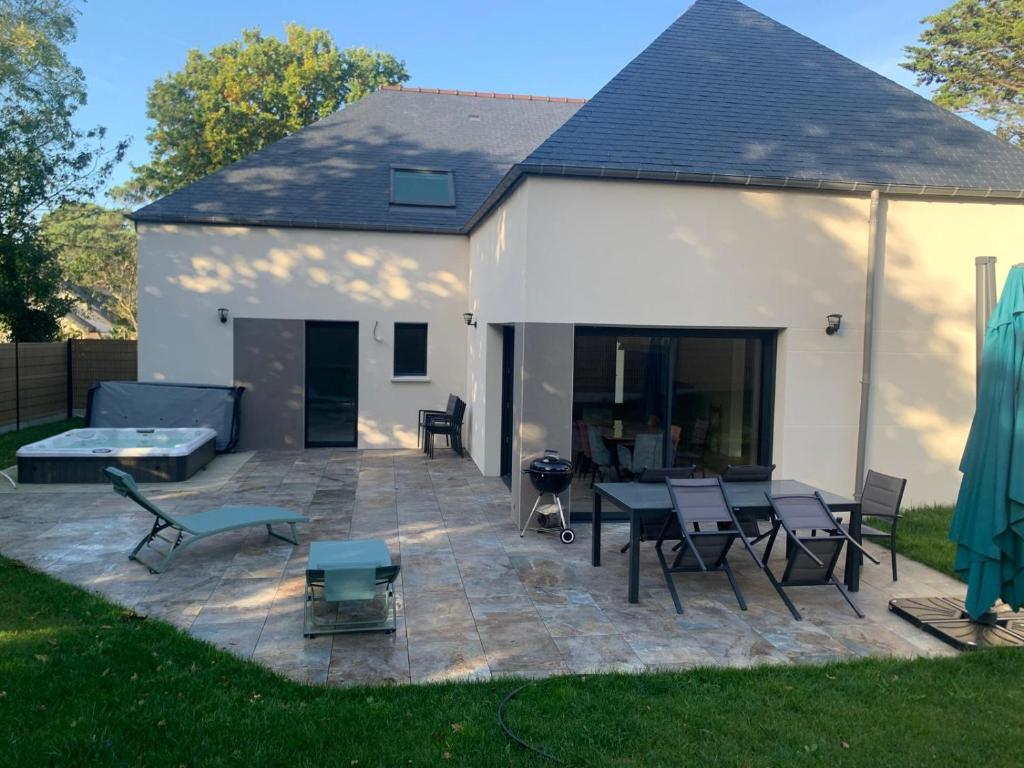 un patio avec une table et des chaises dans une cour dans l'établissement La Maison des As - Neuve - Jacuzzi - bord de mer, à Erquy