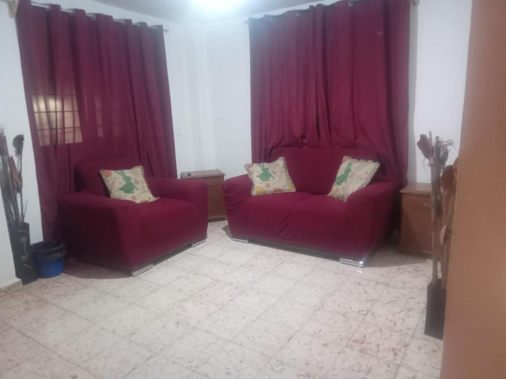 2 sofás rojos en una sala de estar con cortinas rojas en Departamento para 5 o 7, en Uruapan del Progreso