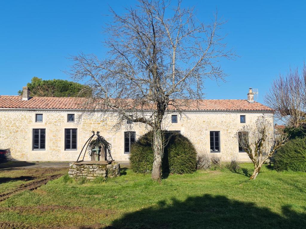 une vieille maison en pierre avec un arbre en face de celle-ci dans l'établissement La Galerne, à Montpellier-de-Médillan