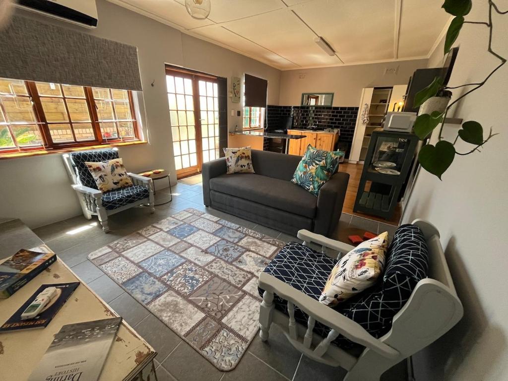 ein Wohnzimmer mit Sofa und Tisch in der Unterkunft Charming Garden Cottage in Gqeberha