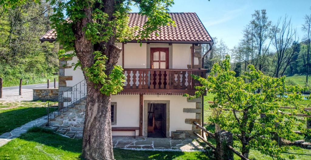 a small house with a balcony and a tree at Hiška Kovačija-Riverside Boutique Retreat in Vremski Britof