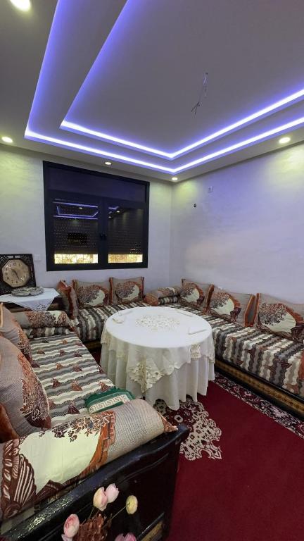 una sala de estar con mesa y sofás y una habitación con techo azul. en Spacious apartment, en Settat