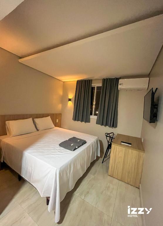 a hotel room with a bed and a television at Izzy Hotel in Uberlândia