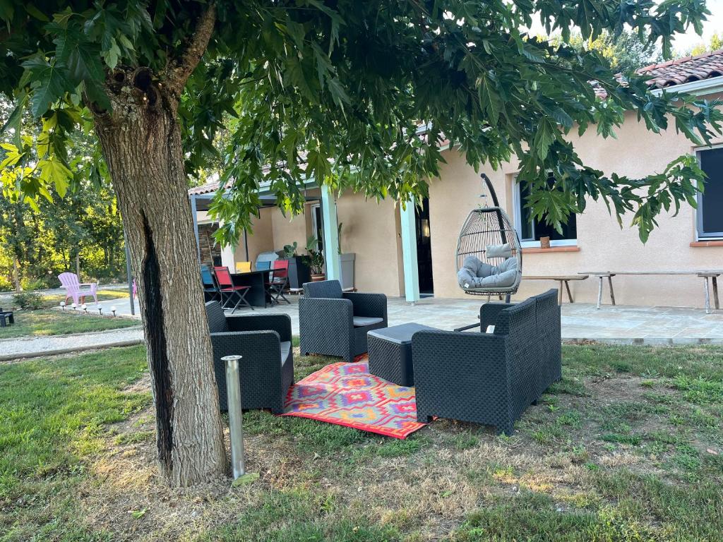 un groupe de chaises et une balançoire sous un arbre dans l'établissement Gite de Gabi Jacuzzi, à Pompignan