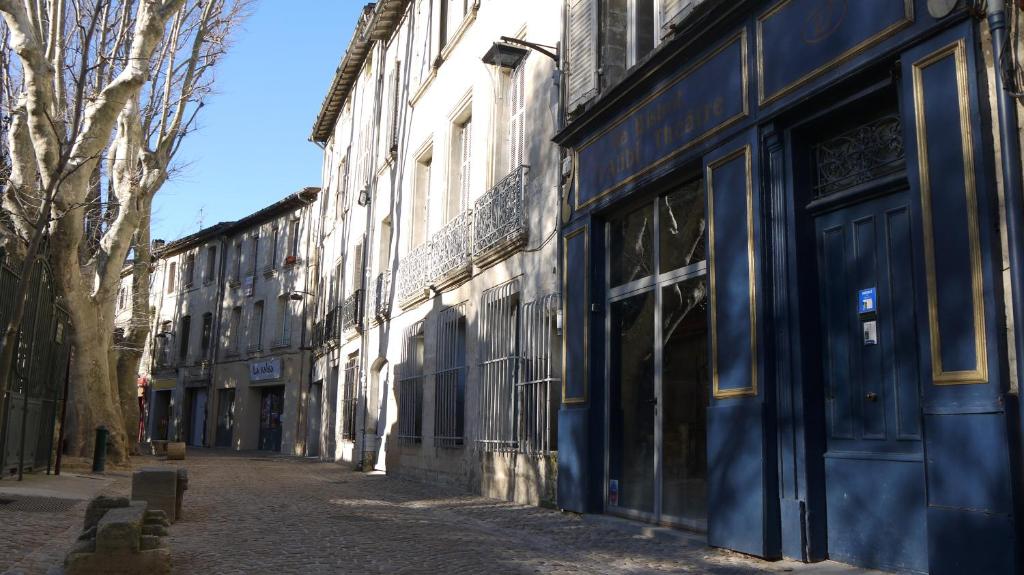 une rue vide avec des portes bleues sur un bâtiment dans l'établissement Appartements des Teinturiers, à Avignon