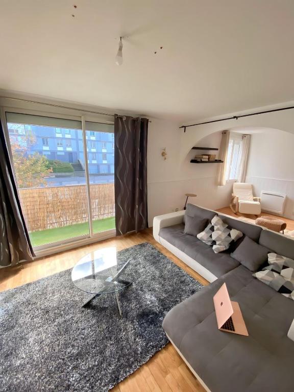 un salon avec un canapé et une table en verre dans l'établissement Appartement proche centre-ville, à Brest